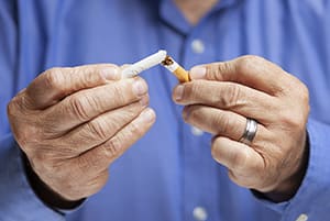 Closeup of hands breaking cigarette in half.
