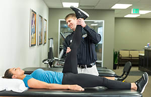 Physical therapist working with a female on leg stretches.